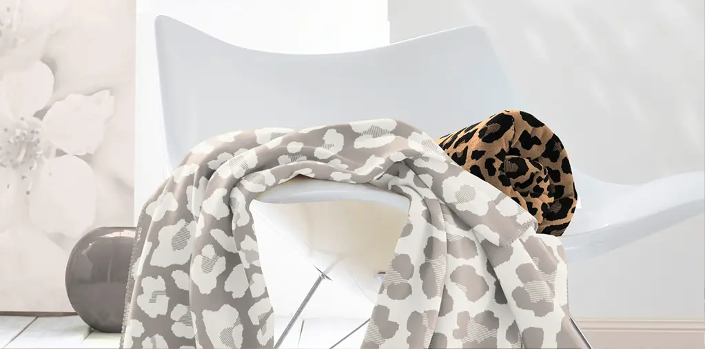 Dekorativer Designstuhl mit gemusterter Kuscheldecke und Kissen im Leoparden-Look – modernes Wohnaccessoire für gemütliches Wohnzimmer, stilvolle Einrichtung und trendige Textilien.